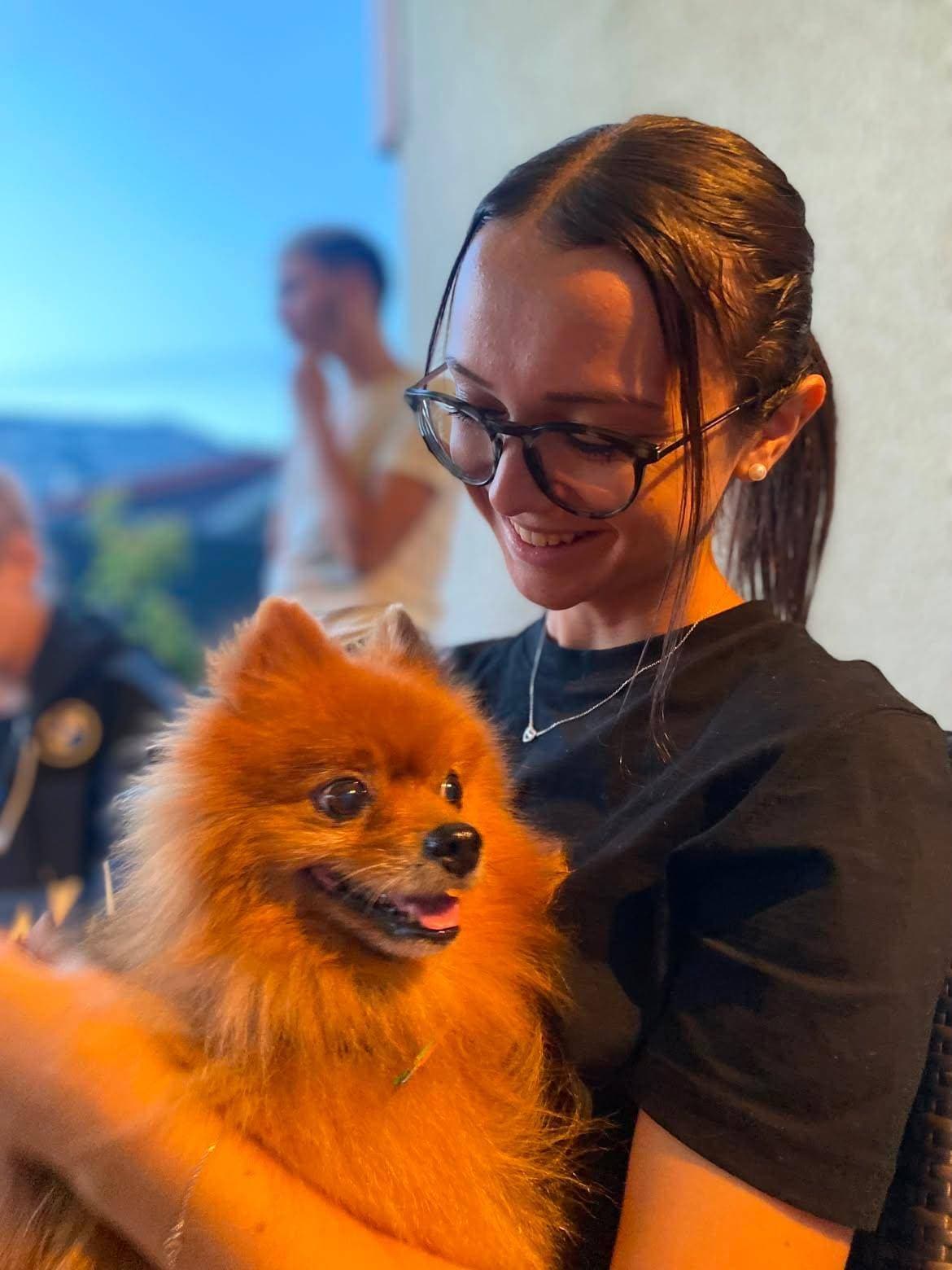 Eva sourit à un poméranien roux qu’elle tient dans ses bras