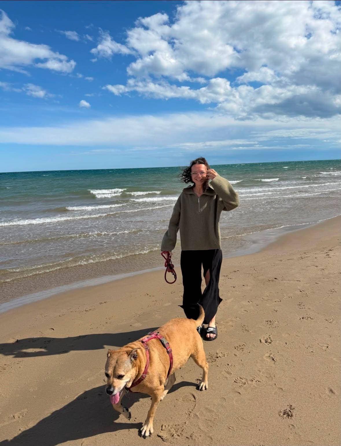 Eva marche sur une plage avec un chien en laisse, face à la mer